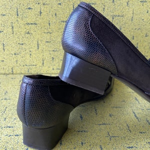 May include: A pair of brown heeled shoes with a snakeskin pattern. The shoes have a low block heel and a pointed toe.