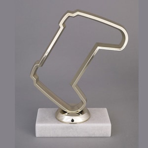 May include: A silver-colored metal trophy shaped like a video game controller, on a white marble base.