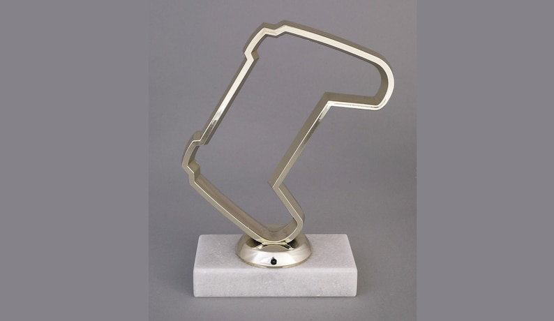 Peut inclure: Un troph&eacute;e en m&eacute;tal argent&eacute; en forme de manette de jeu vid&eacute;o, sur un socle en marbre blanc.