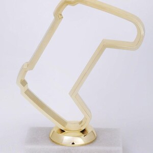 Peut inclure: Un troph&eacute;e dor&eacute; en forme de circuit de course, avec une base en marbre blanc.