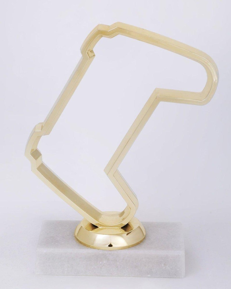 Peut inclure: Un troph&eacute;e dor&eacute; en forme de circuit de course, avec une base en marbre blanc.