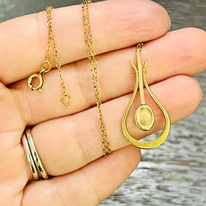 Puede incluir: Un collar de cadena de oro con un colgante en forma de l&aacute;grima con una piedra redonda en el centro.