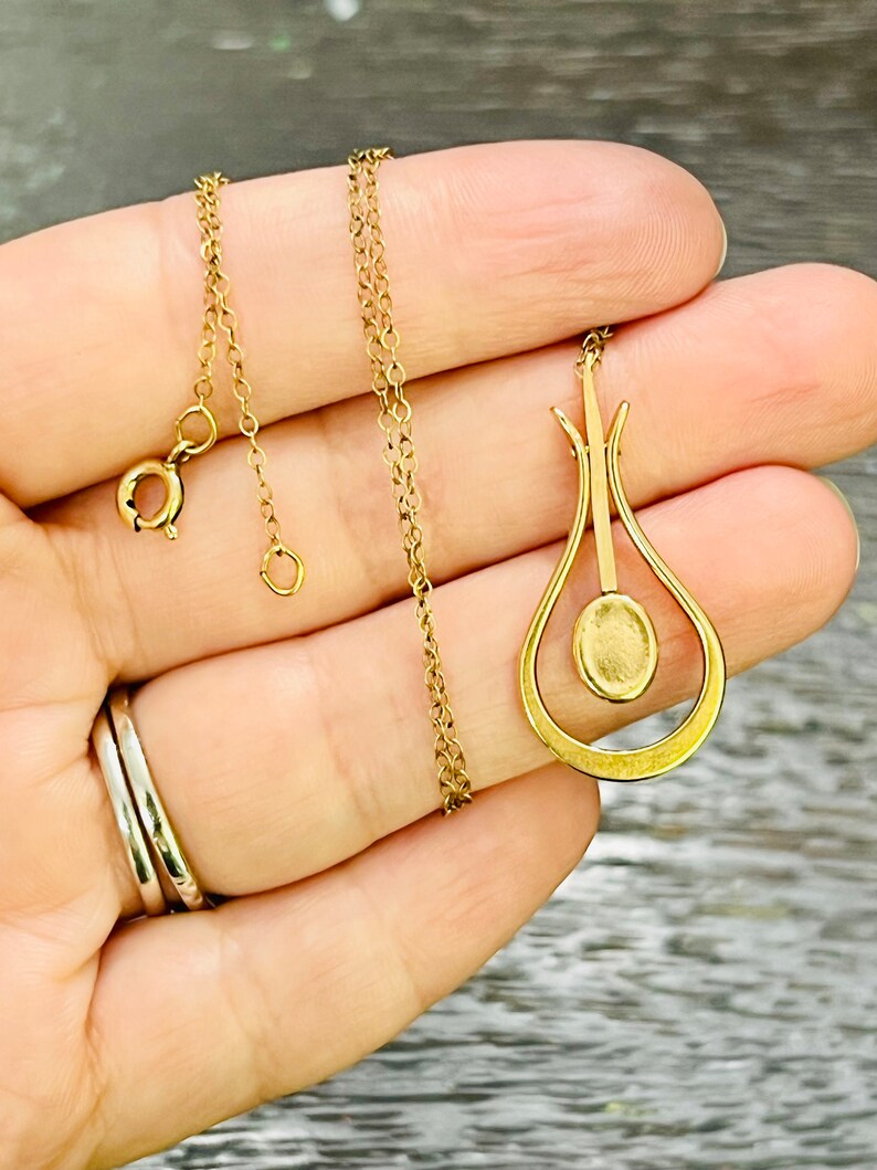 Puede incluir: Un collar de cadena de oro con un colgante en forma de l&aacute;grima con una piedra redonda en el centro.