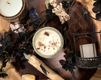 May include: A wooden tray featuring a skeleton figurine, a candle, a jar of wax, and a metal birdcage. The tray is adorned with black flowers and crystals.