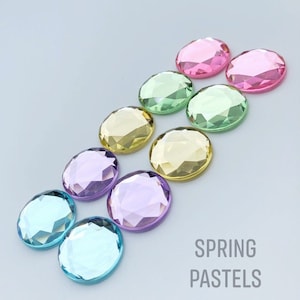 May include: Assortment of pastel colored round rhinestones. The colors are pink, green, yellow, purple, and blue. The rhinestones are arranged in a rainbow pattern. The text "SPRING PASTELS" is written below the rhinestones.