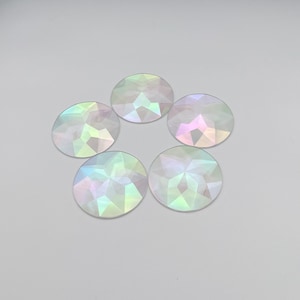 May include: Five iridescent round glass gems with a faceted design. The gems are arranged in a star shape on a white background.