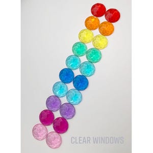 May include: A collection of faceted, round, colorful gems arranged in a diagonal line. The gems transition through the colors of the rainbow, from red to pink. The text "CLEAR WINDOWS" is at the bottom.