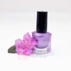 May include: A bottle of purple nail polish with a black cap. The bottle is sitting on a white surface with a pink flower.