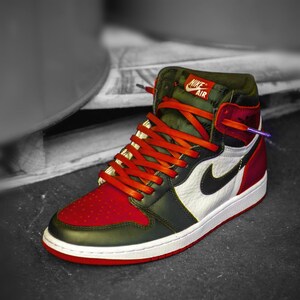 May include: A pair of red and green high-top sneakers with orange laces and a white swoosh logo. The sneakers have the text "Nike Air" on the side.