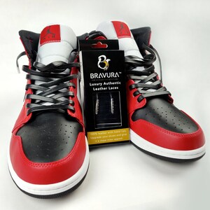 May include: A pair of red and black sneakers with black leather laces. The laces are branded with the text "BRAVURA&trade; Luxury Authentic Leather Laces".