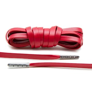 May include: Red leather shoelaces with silver metal aglets. The laces are tied in a knot and laid out flat.