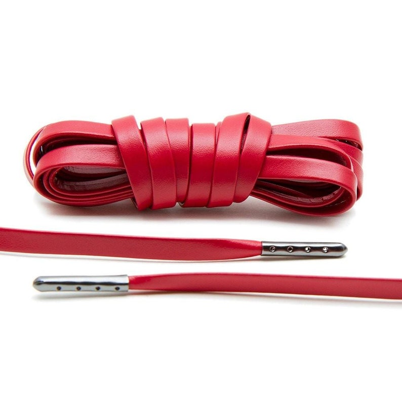 May include: Red leather shoelaces with silver metal aglets. The laces are tied in a knot and laid out flat.