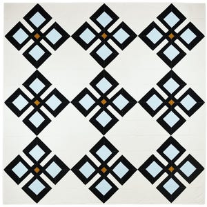 May include: A white quilt with a repeating geometric pattern. The pattern features black diamond shapes surrounding light blue squares, with small brown squares at the center of each floral-like design. The quilt is square and appears to be handmade.