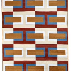 Könnte beinhalten: Eine geometrische Steppdecke mit einem sich wiederholenden Muster aus Rechtecken in Rost-, Creme-, Blau- und Brauntönen. Die Steppdecke hat ein modernes Design mit einer gitterartigen Anordnung der farbigen Blöcke und schafft einen optisch ansprechenden Textil.