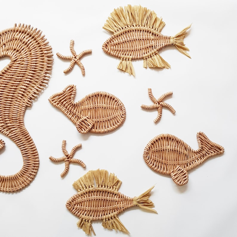 May include: A set of woven sea creature wall decor, including a seahorse, two fish, a whale, and three starfish. The decor is made of natural materials and has a light brown color.