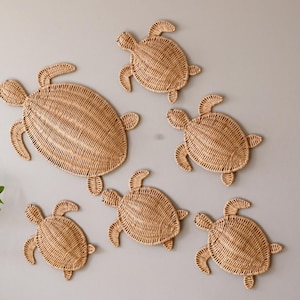 May include: Six woven sea turtle wall decor pieces in various sizes. The turtles are made of natural woven material and are a light brown colour.