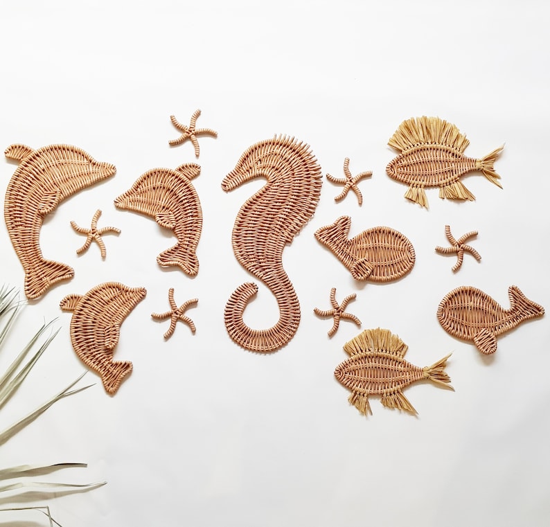 May include: A set of woven sea creature wall decor, including a seahorse, dolphins, starfish, and fish. The decor is made of natural materials and has a light brown color.