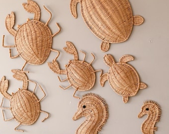 Puede incluir: Decoración mural tejida con criaturas marinas. El conjunto incluye cangrejos, tortugas y caballitos de mar en color beige natural. Los diseños de cangrejos y tortugas tienen detalles, mientras que los caballitos de mar son verticales.