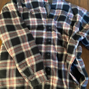 May include: A black, white, and red plaid flannel shirt with a fleece lining. The shirt has a button-up front and long sleeves.