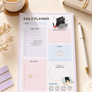 Peut inclure: Un bloc-notes journalier rectangulaire avec une bordure violet clair, comprenant des sections pour le travail, les priorités, les notes, la vie quotidienne et la gratitude. Le design inclut des illustrations de chat noir et du texte.