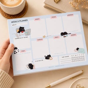 Può includere: Un blocco note per la pianificazione settimanale azzurro con illustrazioni di gatti neri in varie attività. Il layout include sezioni per i giorni della settimana, una lista di cose da fare chiamata Pawrities of the Week, un tracker delle abitudini e il testo Mocha Cat.