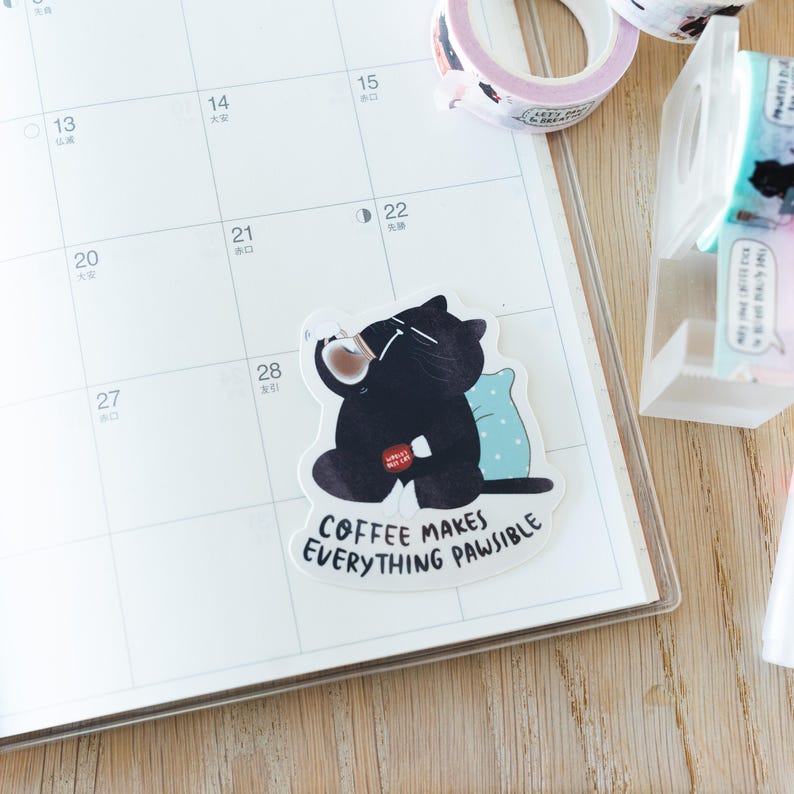 Pu&ograve; includere: Un adesivo di un gatto nero con una tazza di caff&egrave; nella zampa, seduto su un cuscino blu. L'adesivo dice "Il caff&egrave; rende tutto possibile."