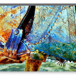 May include: Close-up of a blue and green cowboy boot with intricate stitching and a spur. The boot is worn and has a distressed look.