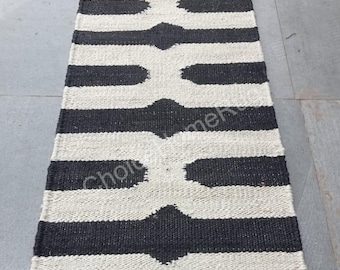 May include: Black and white striped rug with a geometric pattern. The rug is made of natural fibers and has a jute border.