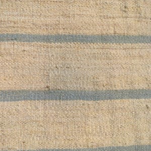 May include: A natural fiber rug with a woven texture and blue stripes. The rug is made of jute and has a rustic look.