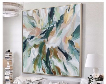 May include: Abstract painting with a white background and green, gold, and pink brushstrokes. The painting is framed in a gold frame and is hanging on a white wall.
