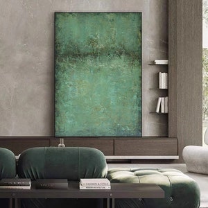 May include: Abstract painting with a green, blue, and brown colour scheme. The painting is framed in black and hangs on a wall in a modern living room.