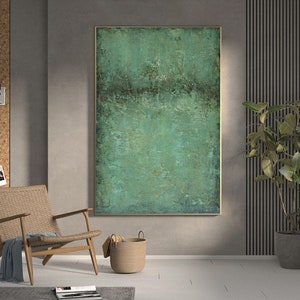 May include: Abstract painting with a green and brown colour scheme. The painting is framed in a gold frame and hangs on a grey wall.