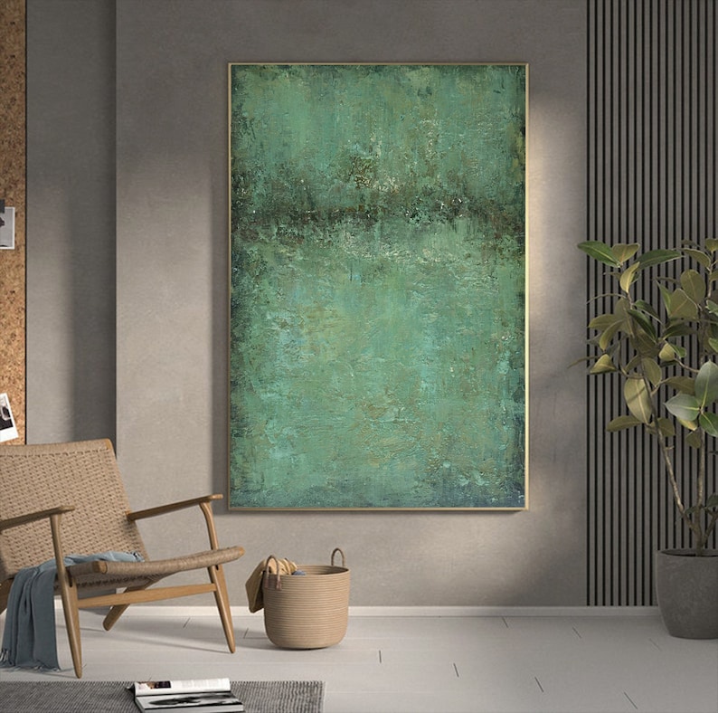 May include: Abstract painting with a green and brown colour scheme. The painting is framed in a gold frame and hangs on a grey wall.