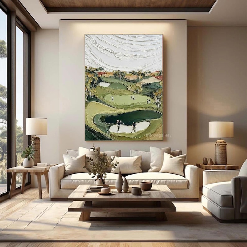 May include: An abstract golf course painting in shades of green, white, and brown hangs above a white sofa. The artwork depicts a golf course with players, trees, and a textured sky. The room features a wooden coffee table, side tables, and lamps.