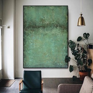 May include: Abstract painting with a green, blue, and brown colour scheme. The painting has a textured surface and a horizontal line across the middle. The painting is hanging on a white wall in a room with a chair and a plant.