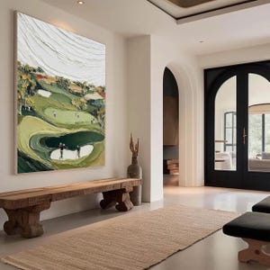 May include: Large framed oil painting depicting a golf course with players. The artwork features a textured, impasto style with shades of green, white, and brown. The painting hangs above a rustic wooden bench in a well-lit hallway.