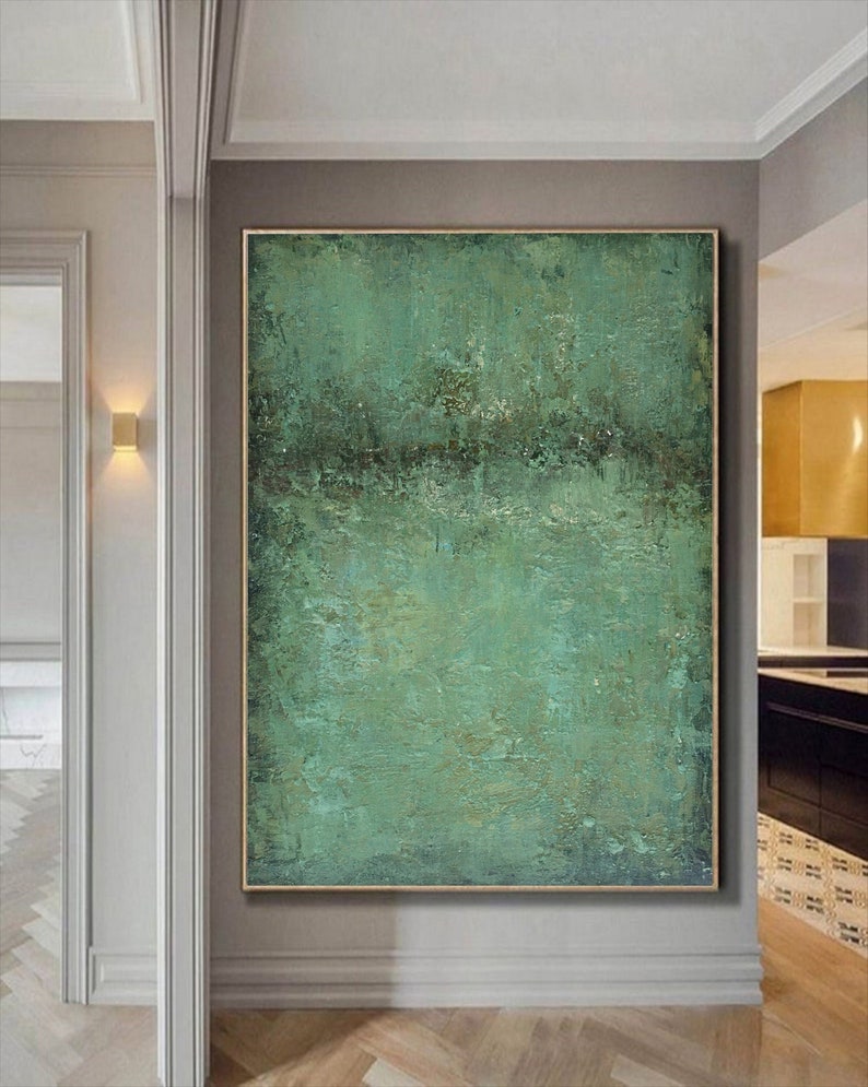 May include: Abstract painting with a textured green and brown colour scheme. The painting has a horizontal line across the middle, with a lighter green above and a darker green below. The painting is framed in a gold frame.