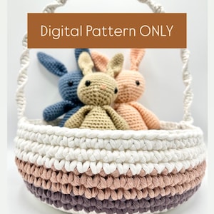 May include: A white crocheted basket with a rope handle and a pink, white, and gray striped base. Three crocheted bunny toys are inside the basket. The text "Digital Pattern ONLY" is on a brown rectangle.