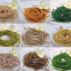 May include: Assortment of 10 spools of metallic cord in various colours, including gold, silver, green, brown, and pink. The cord is arranged in a circular pattern on a white surface.