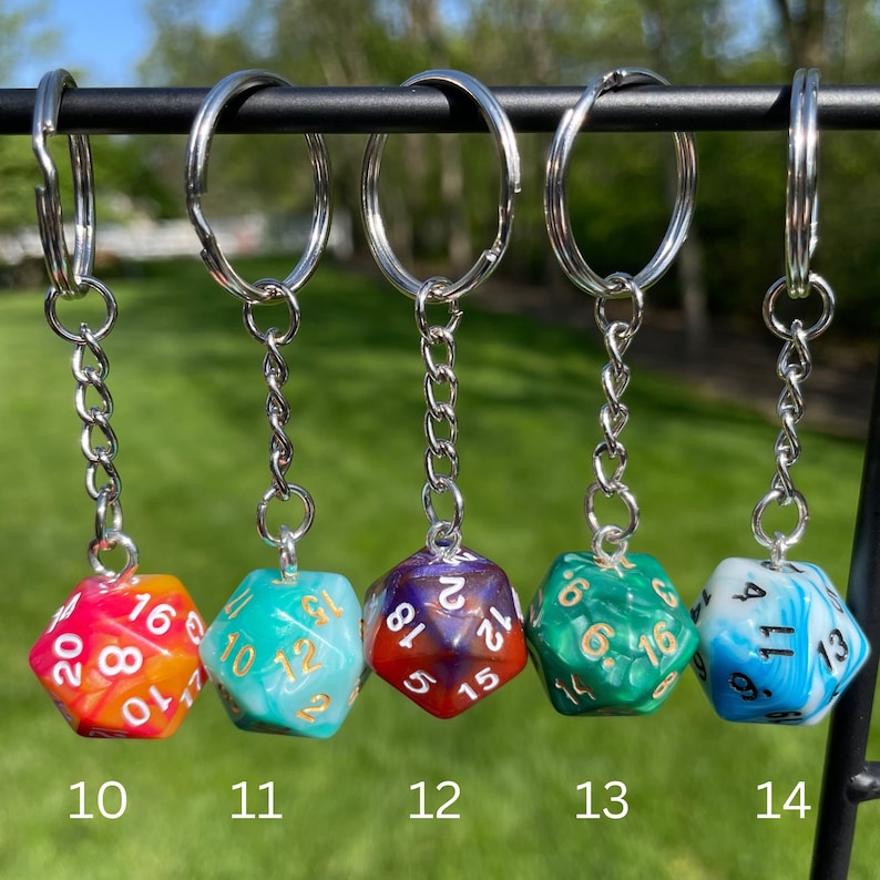May include: Five multi-colored dice with gold numbers on each side, attached to silver keychains. The dice are numbered 10, 11, 12, 13, and 14.