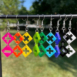 May include: A set of 10 colorful geometric earrings with a rainbow color scheme. Each earring features a double-sided design with a plus sign and a puzzle piece shape.
