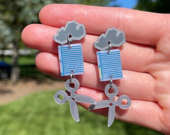 May include: Gray cloud earrings with a blue and white patterned paper clip and gray scissors dangling below.