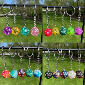 May include: A set of 10 colorful, transparent dice keychains with gold numbers. Each keychain features a different color and number combination. The keychains are attached to silver key rings.