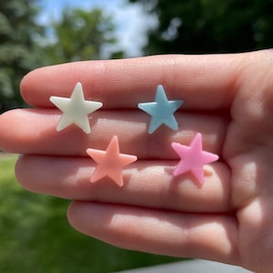 May include: Five star-shaped buttons in different pastel colors. The colors are light blue, light pink, light green, and white.