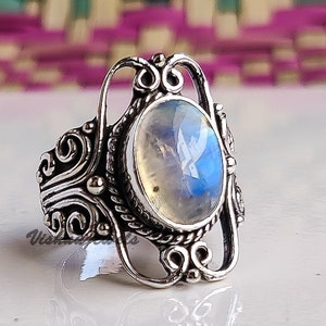 Könnte beinhalten: Ein silberner Ring mit einem großen ovalen Mondstein, der in einem filigranen Design eingefasst ist.