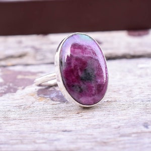 May include: A silver ring with a large oval-shaped pink and green gemstone. The gemstone has a mottled pattern.