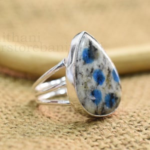 May include: A silver ring with a pear-shaped blue and white gemstone. The gemstone has a speckled pattern of blue and white.