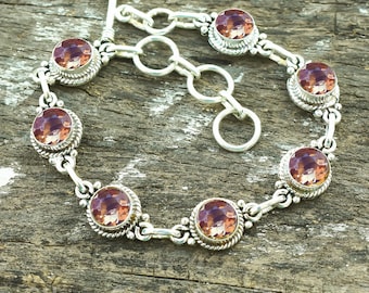 Puede incluir: Un brazalete de plata con cierre de palanca y seis piedras de amatista facetadas. Las piedras están engastadas en biseles de plata y están rodeadas de detalles decorativos de plata.