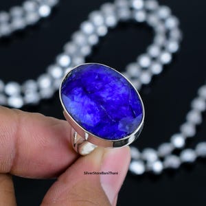 Könnte beinhalten: Ein silberner Ring mit einem großen, ovalen blauen Edelstein. Der Edelstein hat eine tiefe, satte blaue Farbe und ein leicht trübes Aussehen. Der Ring ist in eine schlichte, silberne Fassung gefasst.