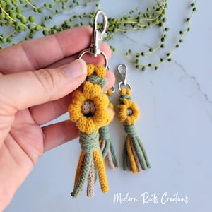 May include: Handmade sunflower keychains with yellow, green, and tan accents. Each keychain features a crocheted sunflower and tassel design, attached to a silver-tone clasp. The keychains are a charming accessory.